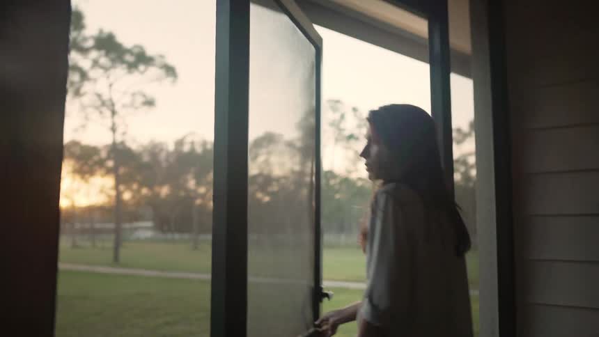 A woman in a rural area walks out of her house
