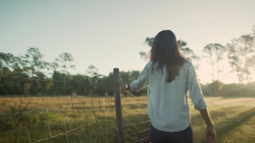 A woman is walking in a rural area at dusk