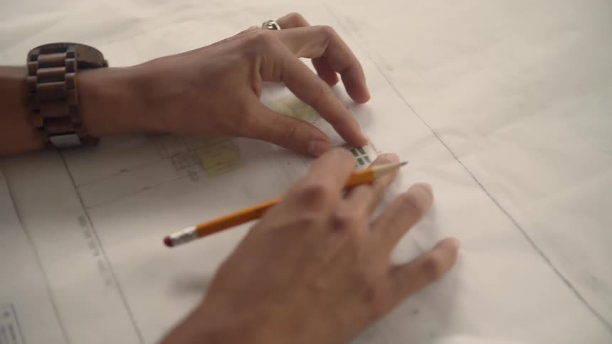 A persons hands with a wristwatch a ring and a pencil moving papers