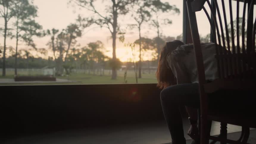 Woman sitting outside on a porch putting on a pair of boots