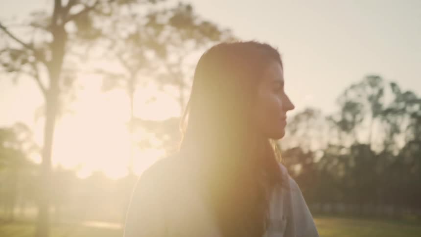 Woman walking towards a house in front of a sunset and opening a door