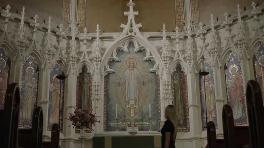 A woman walks across the center of a church