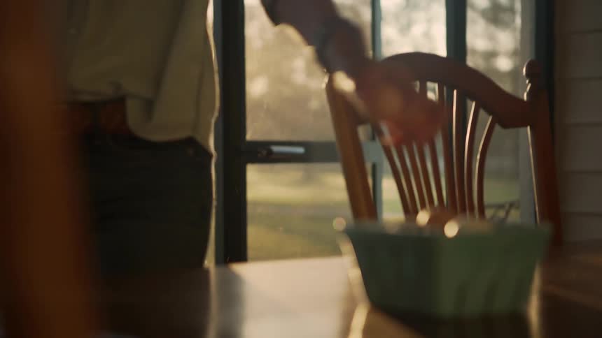 A woman enters her home and puts some eggs in a basket