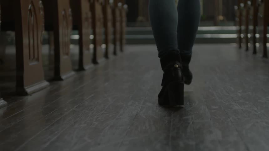 The legs of a woman as she walks up a church aisle