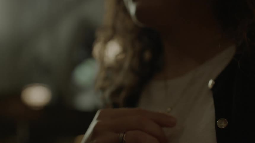 A woman clutches a cross necklace and then lets it fall to her chest