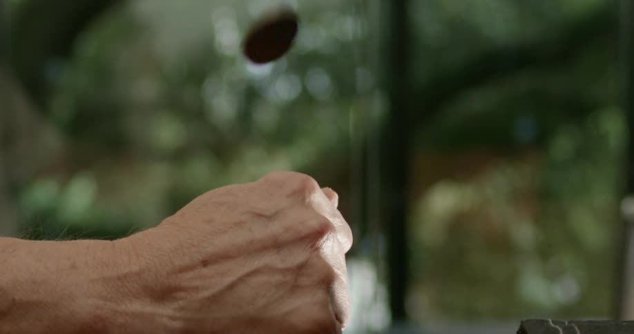 An elderly person flipping a coin in their hand