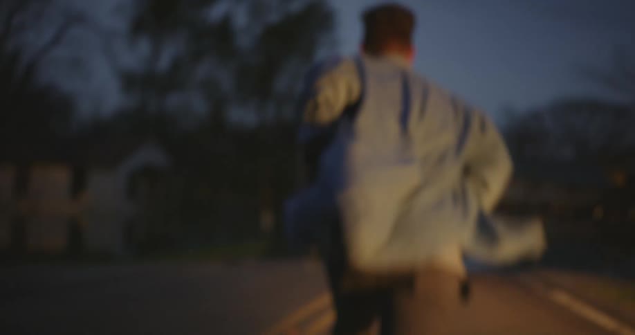 A man exits a truck and runs down the street at night