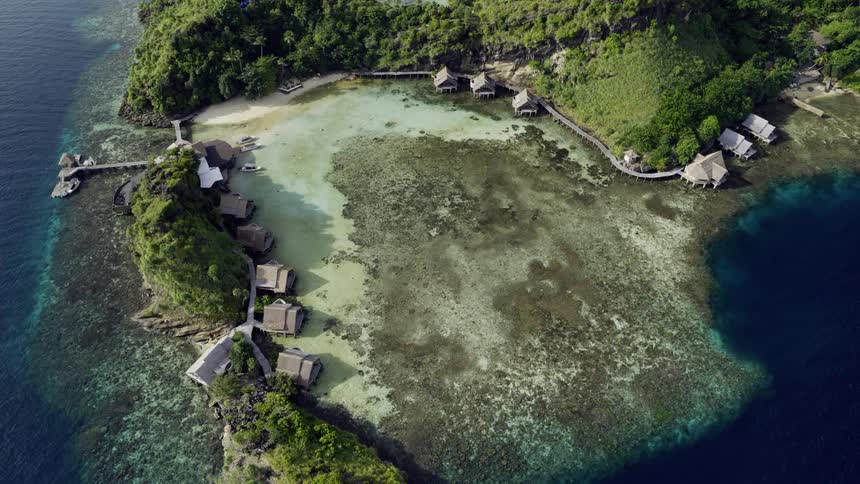 Huts lined along the coast of a large island out at sea