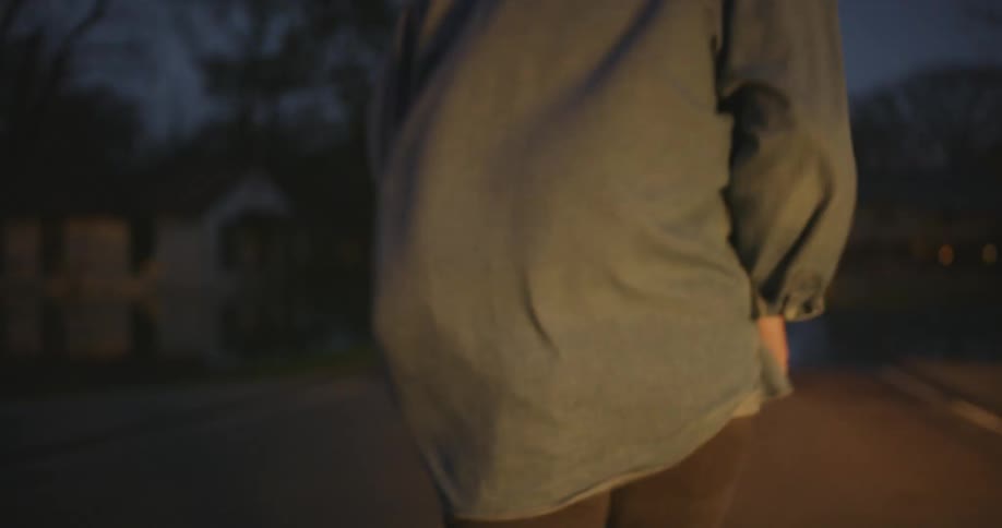 A man exits a vehicle in a neighborhood and runs down the street at dusk