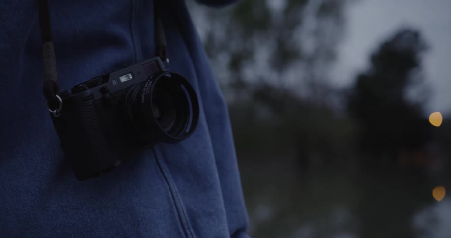 Close up of a camera alongside a persons hip on a dark cloudy day outdoors