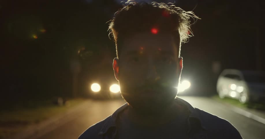 A man is standing outdoors by some cars
