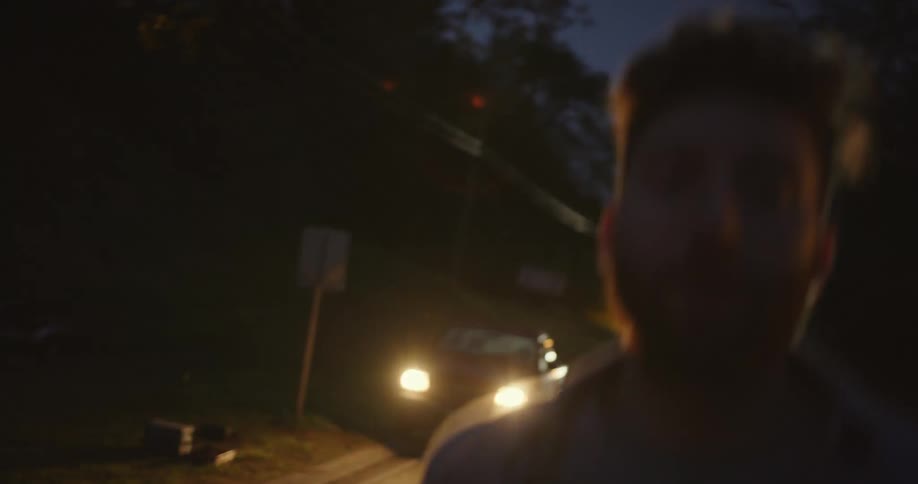 A man parks his car on the side of the road in a neighborhood and runs down the block to a house