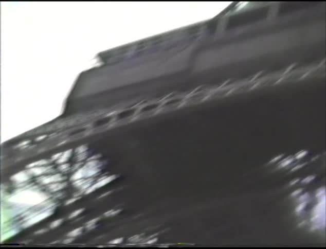 This is a ground up view of the eiffel tower in paris on an overcast day with lots of cars parked on the street