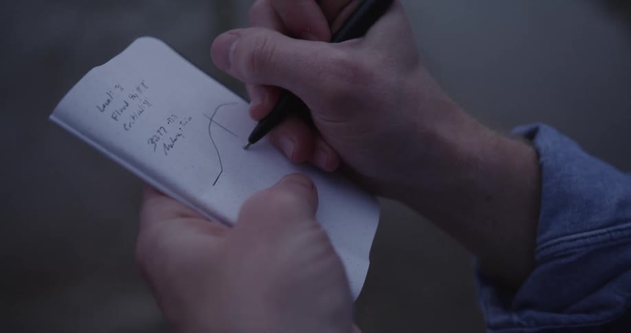 A man writes in a small notebook