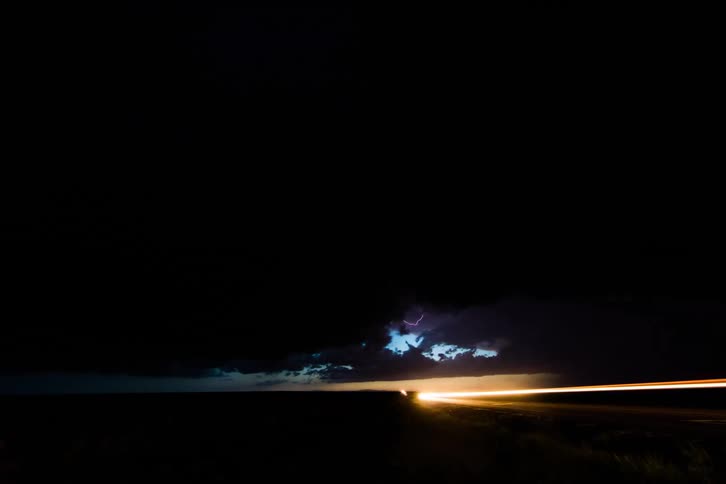 Dark storm clouds in the sky with lightning and cars zooming by