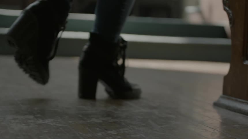 Female feet in booties walk up a church aisle then to a pew