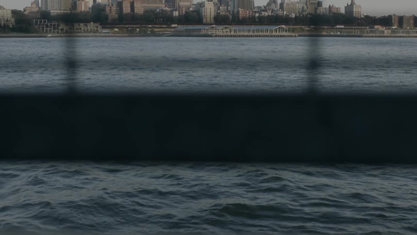 Water and a city can be seen beyond a fence