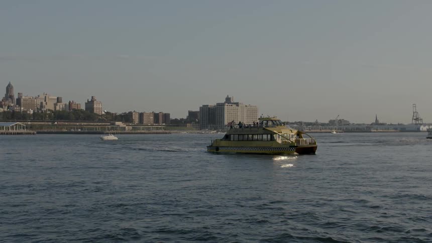 A large ferry is moving away from a city at sunset