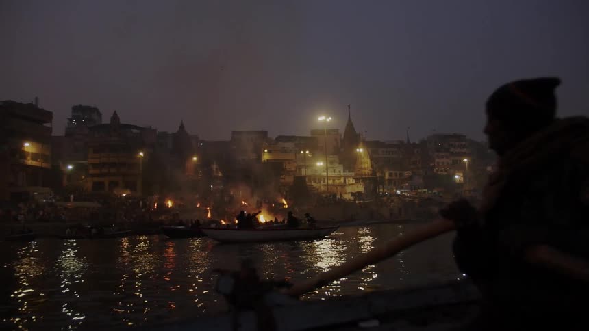 Brightly lit coastal city next to a river with people in a small boat