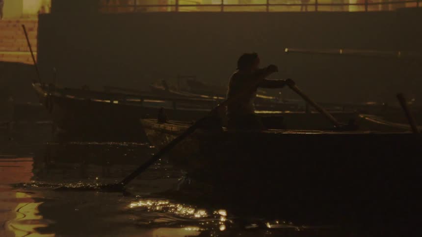 A person with paddles rolling a rowboat in a dock with boats in the background