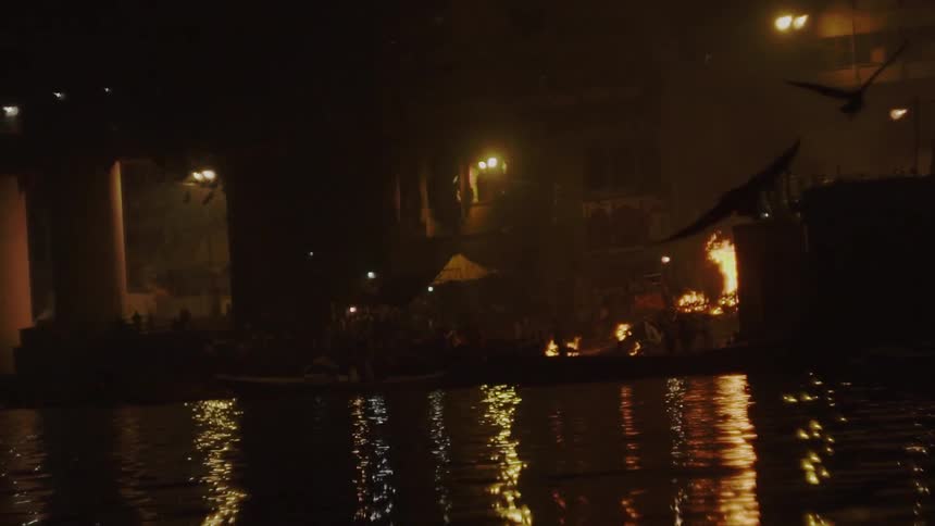 Pile of rubble on fire on the outskirts of a city shoreline at night