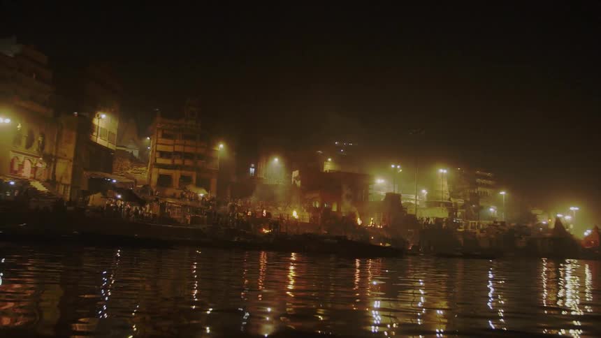 Buildings in a developing city reflect off a lake at night