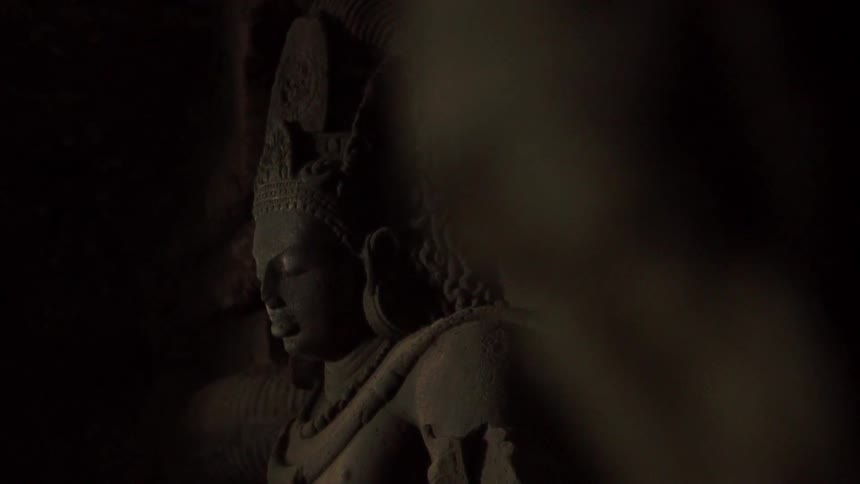 A statue of buddha has the religious figure wearing a decorative crown with his eyes closed