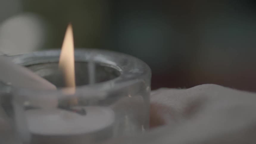 Close up of a hand holding a candle as it is being lit