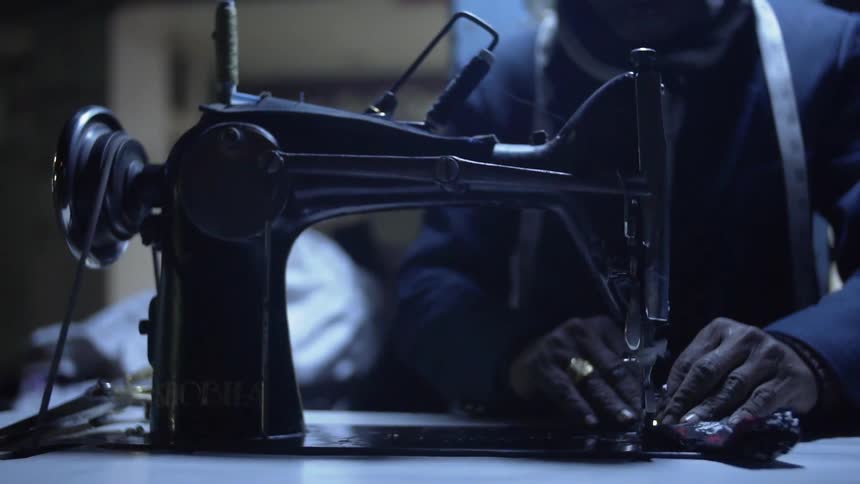 African american person is sewing material with a sewing machine