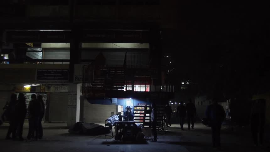 People walking around in a shopping district at night