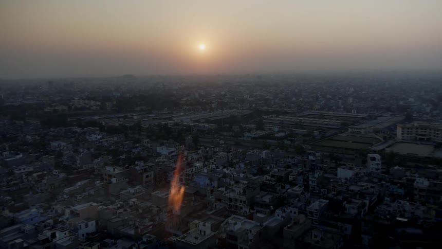 The sun setting over city buildings on a hazy day