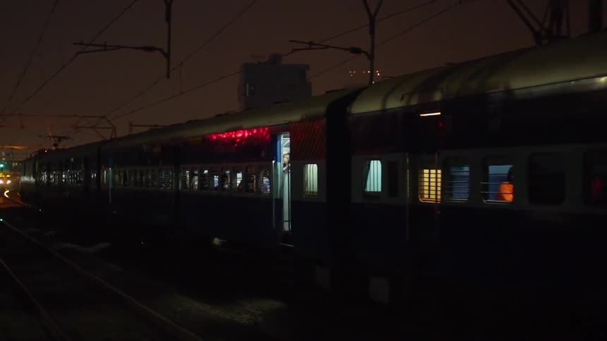 Passing traffic casts a shadow on a stopped passenger train in a city