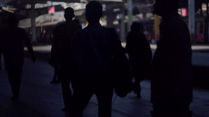 Passengers watch and wait as a yellow train pulls into the station