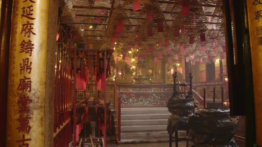 An interior of an asian temple in red gold black with stairs leading up with railing