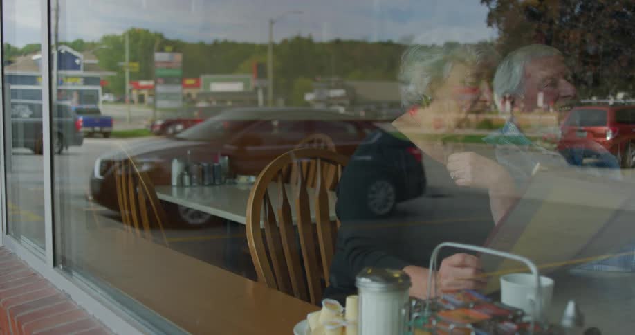 Husband and wife sit at a table in a diner and order food from a menu