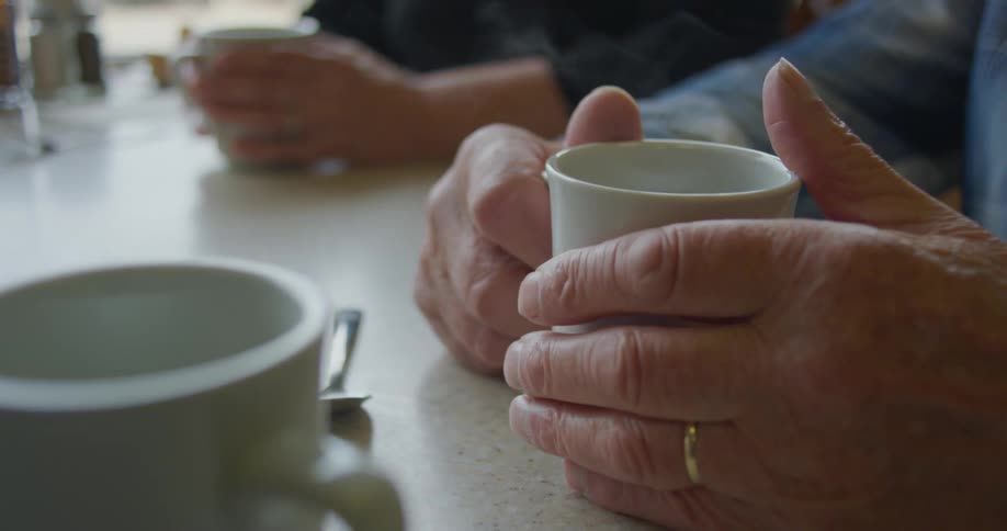 Men sitting down holding mugs with hot beverages
