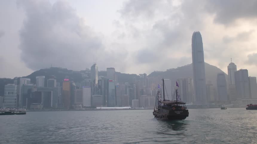 A boat sails slowly towards a large city