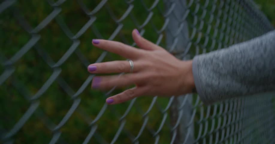 Womans hand running across a metal fence