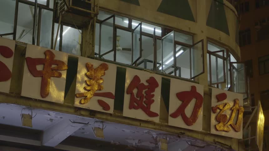 Building with open windows and spinning fan inside with mandarin writing on the outside