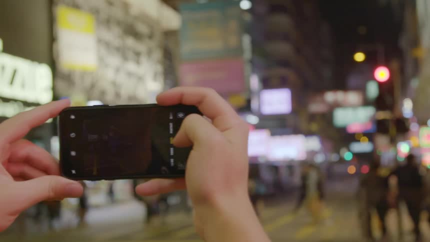 A man takes a picture of a busy street downtown at night