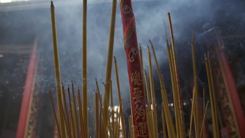 Smoke floating away from sticks of burning incense