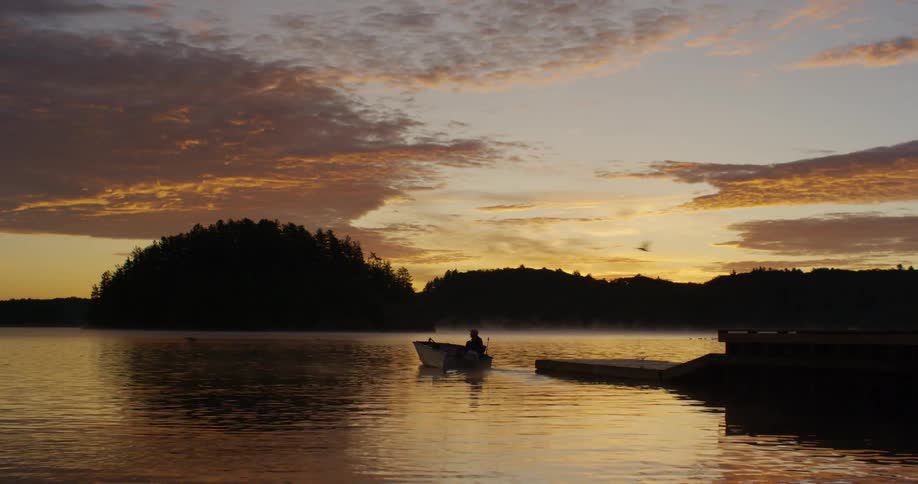 A man takes off from a pier on his boat at dusk