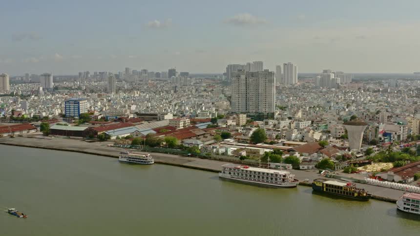 A coastal city with boats buildings and trees with the sky and clouds in the background
