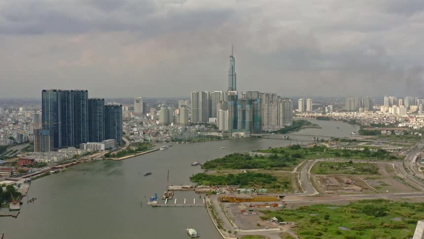 Boats sail in a wide river that runs through a bustling city