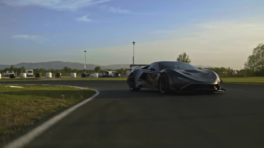 Black sports car speeding on a race track in the middle of the day