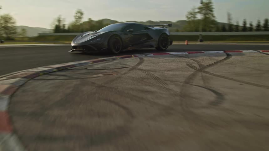 A car is driving on a racetrack at dusk