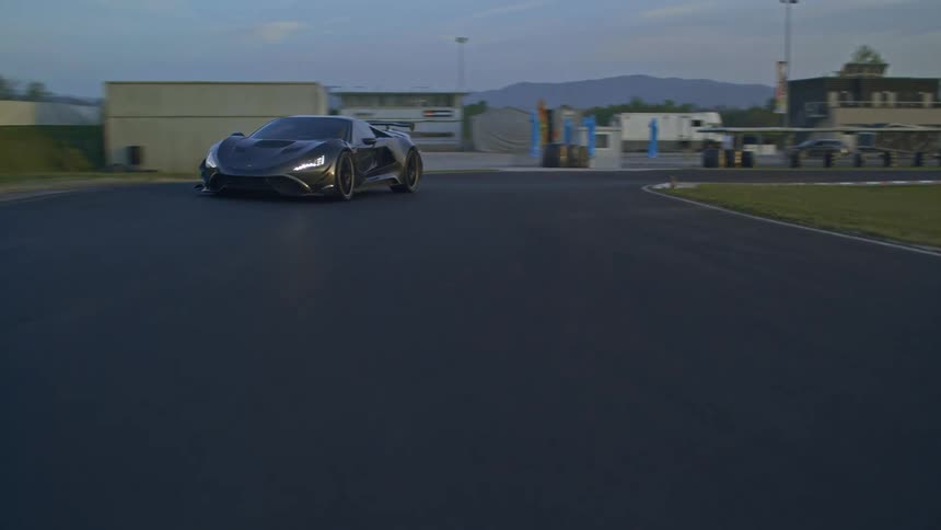 Black sports car speeding on a racetrack at sunset