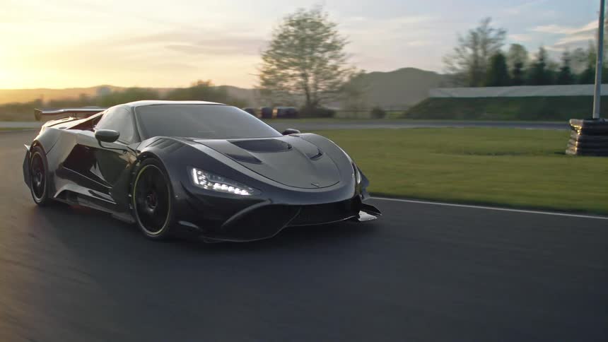 A black sports car is driving on a race track at dusk