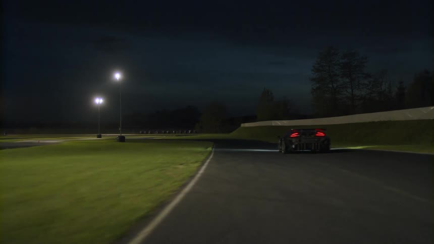 A car is driving on a track at night during spring