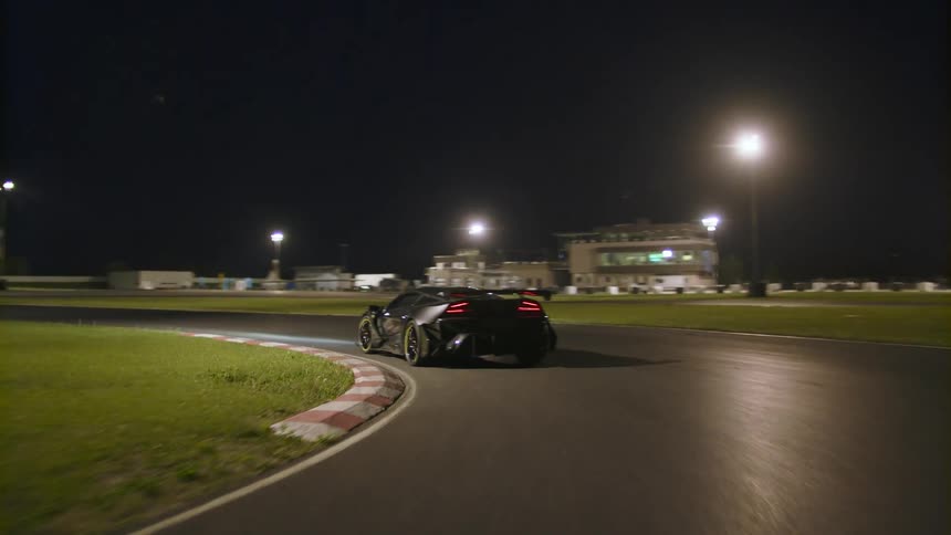 Black sports car speeding on a race track at night